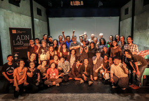 A large group of people standing in a room smiling into the camera. To the left is a standing banner with the words 'ADN Lab' on it.