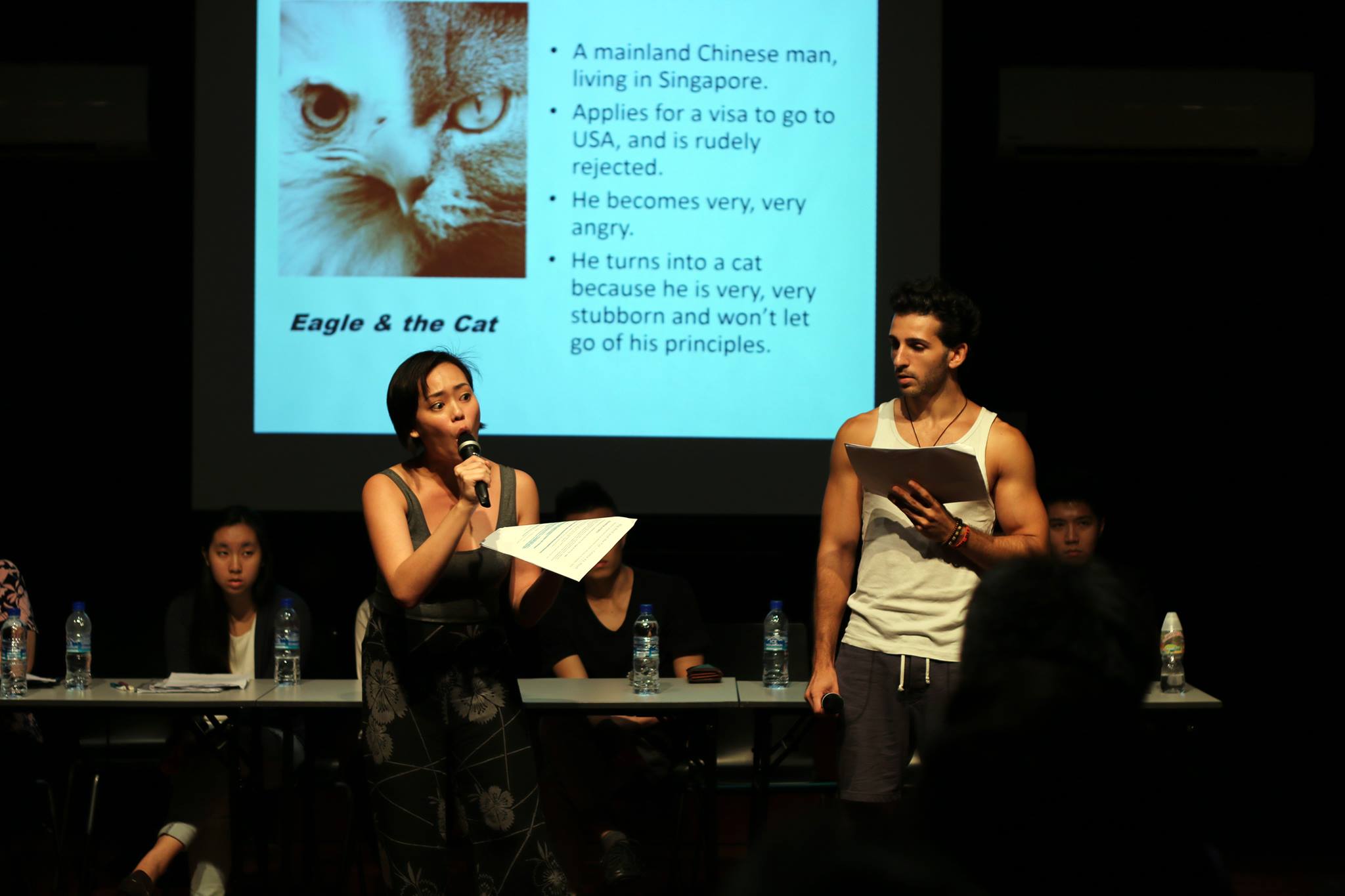 The photograph is of two performers Terri and Nathan performing a short excerpt from "The Eagle and the Cat". There is a projection of a slide in the background. The photograph is of two performers Terri and Nathan performing a short excerpt from "The Eagle and the Cat". There is a projection of a slide in the background.
