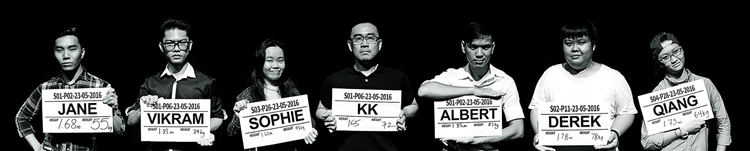 Seven persons, in black and white, stand in a row, holding boards with character names and heights written on them.