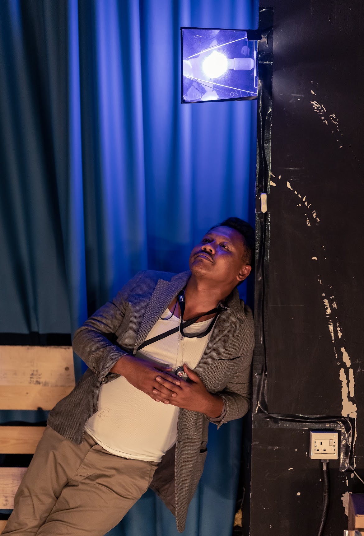 A male-presenting person is leaning his upper body on a wall.