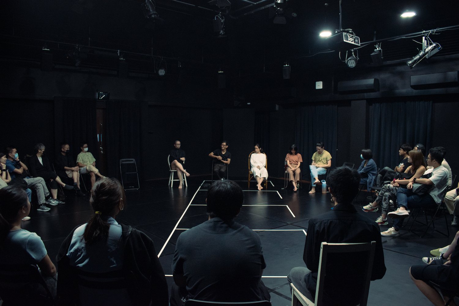 An image of the Black Box with members of ZOBO Company and audience for the work-in-progress showcase seated in a square.