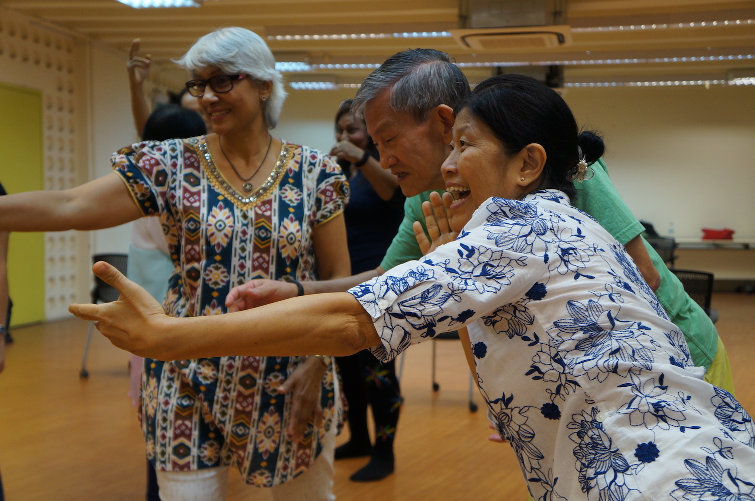 Three elderly persons gesturing broadly with their arms.