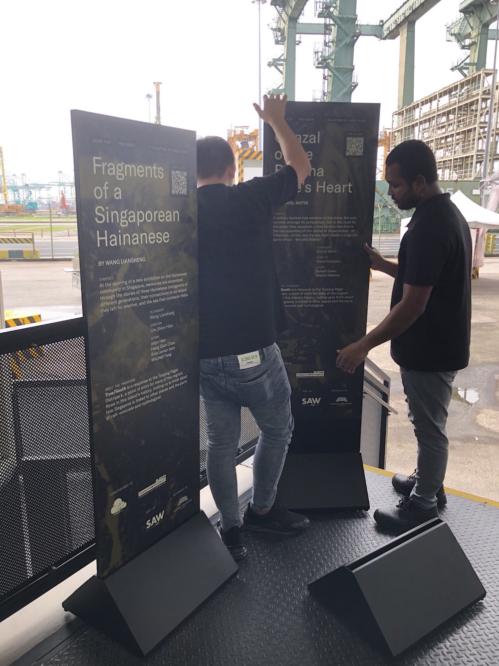 Two persons setting up two tall installation boards.