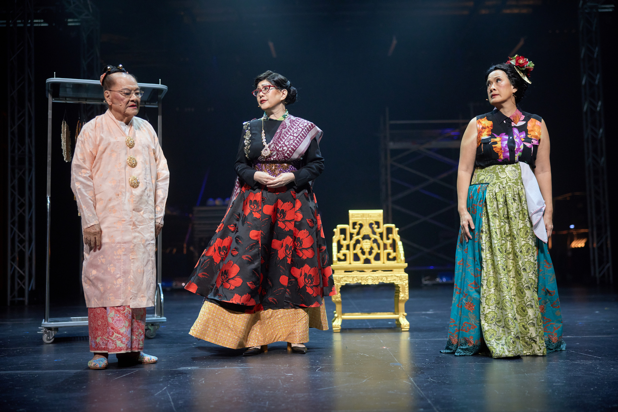 Three persons in elaborate colourful costumes standing and speaking to one another.