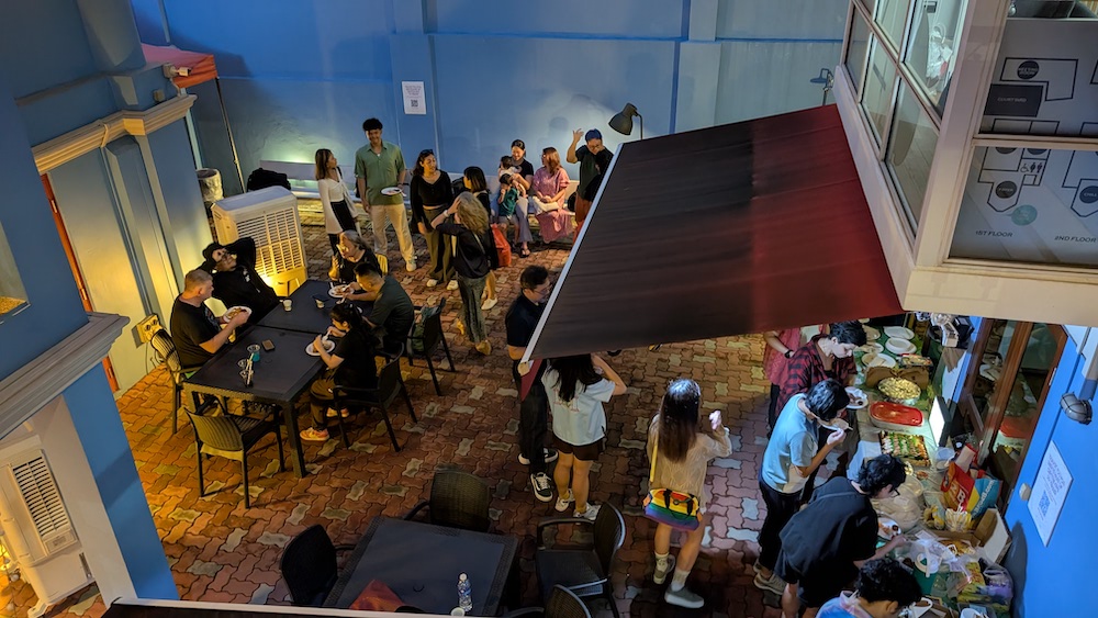 A large group of people mingling in a dimly lit outdoor courtyard.