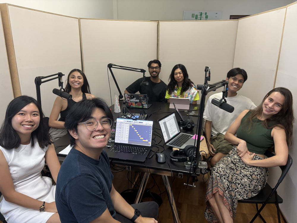 A group of people seated around black tables, smiling.
