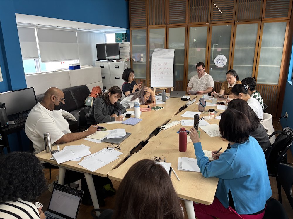 A group of people seated around a table with papers strewn in front of them.