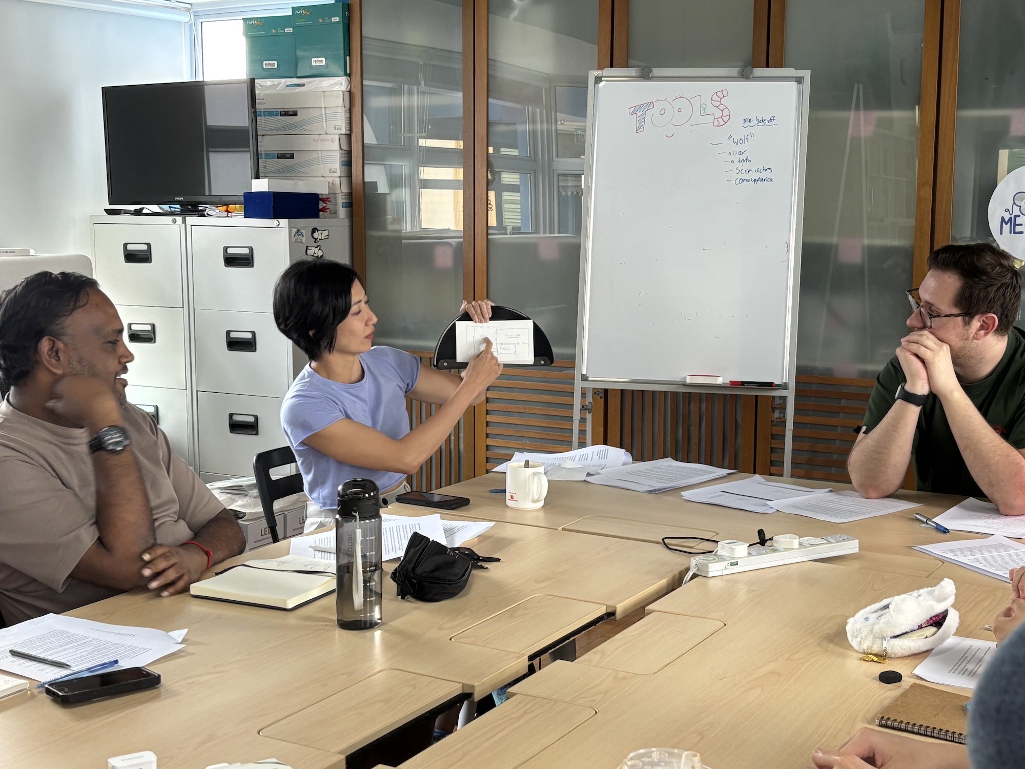 A person holding up some paper and pointing at it, while two others look on.