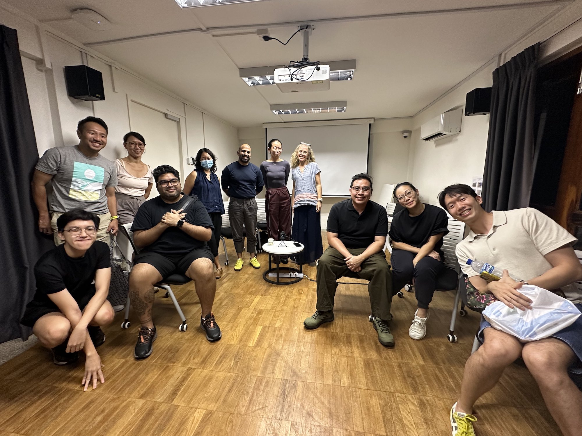A group of people seated and standing together, smiling at the camera. A group of people seated and standing together, smiling at the camera.