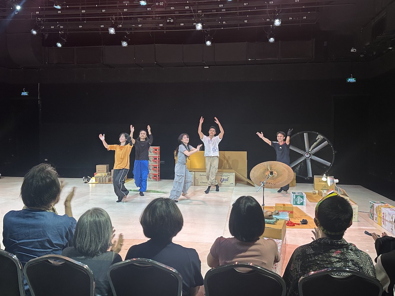 Five performers dancing and jumping on a minimalist stage with some colourful props. Five performers dancing and jumping on a minimalist stage with some colourful props.