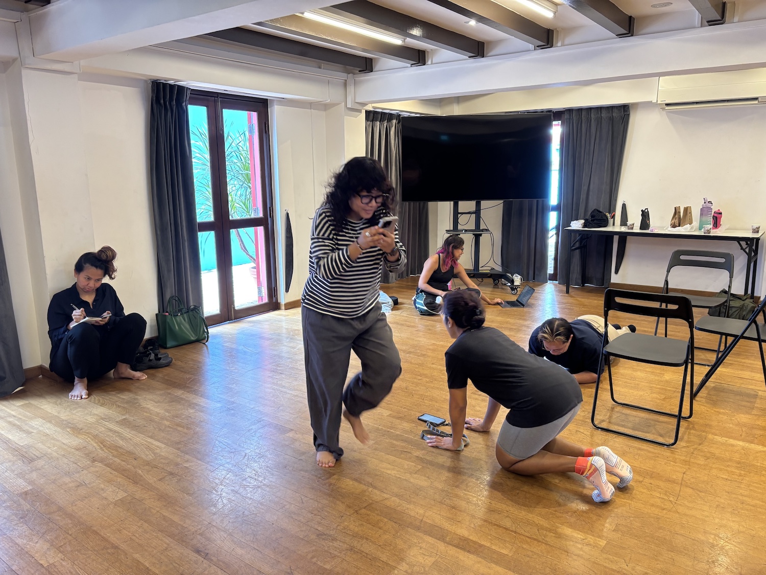 Five people moving around a spacious room, in various contortions.