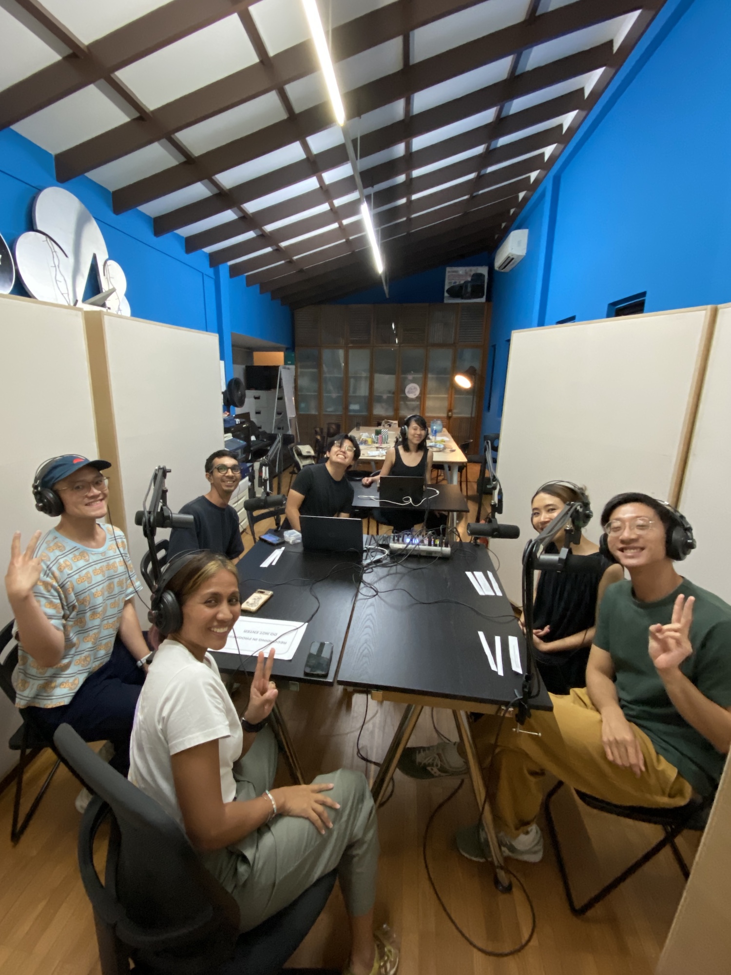 Several persons seated around two black tables, smiling at the camera.