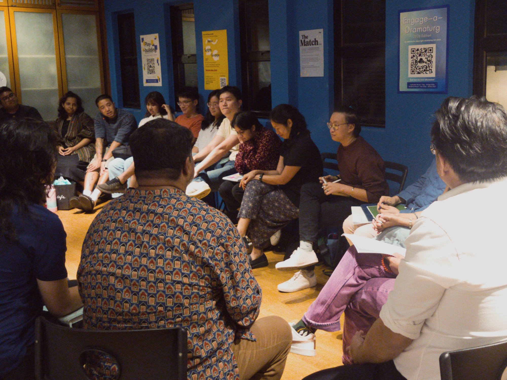 Several people seated in a circle in a small office.