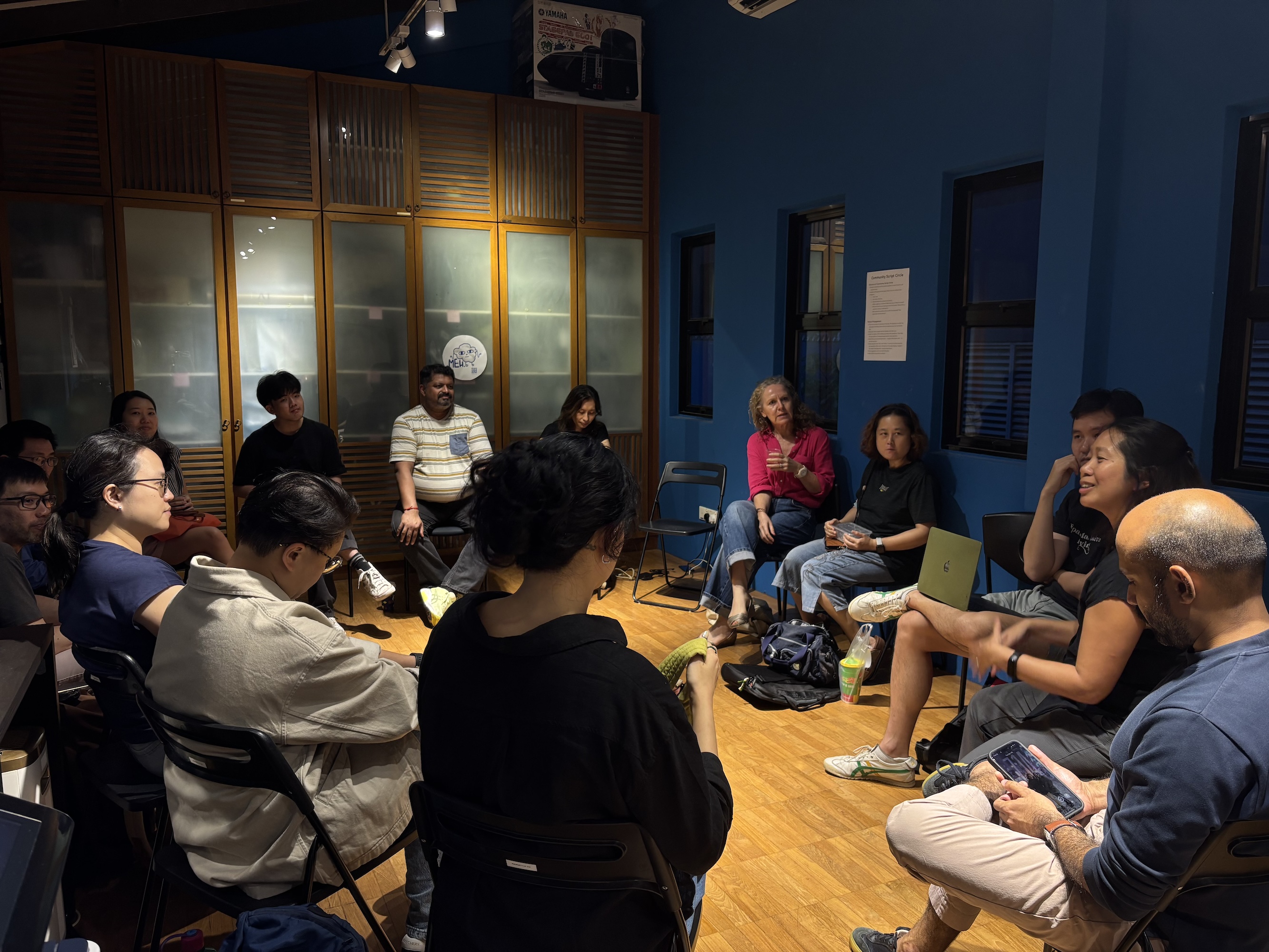 A group of people sitting in a circle in a small office.