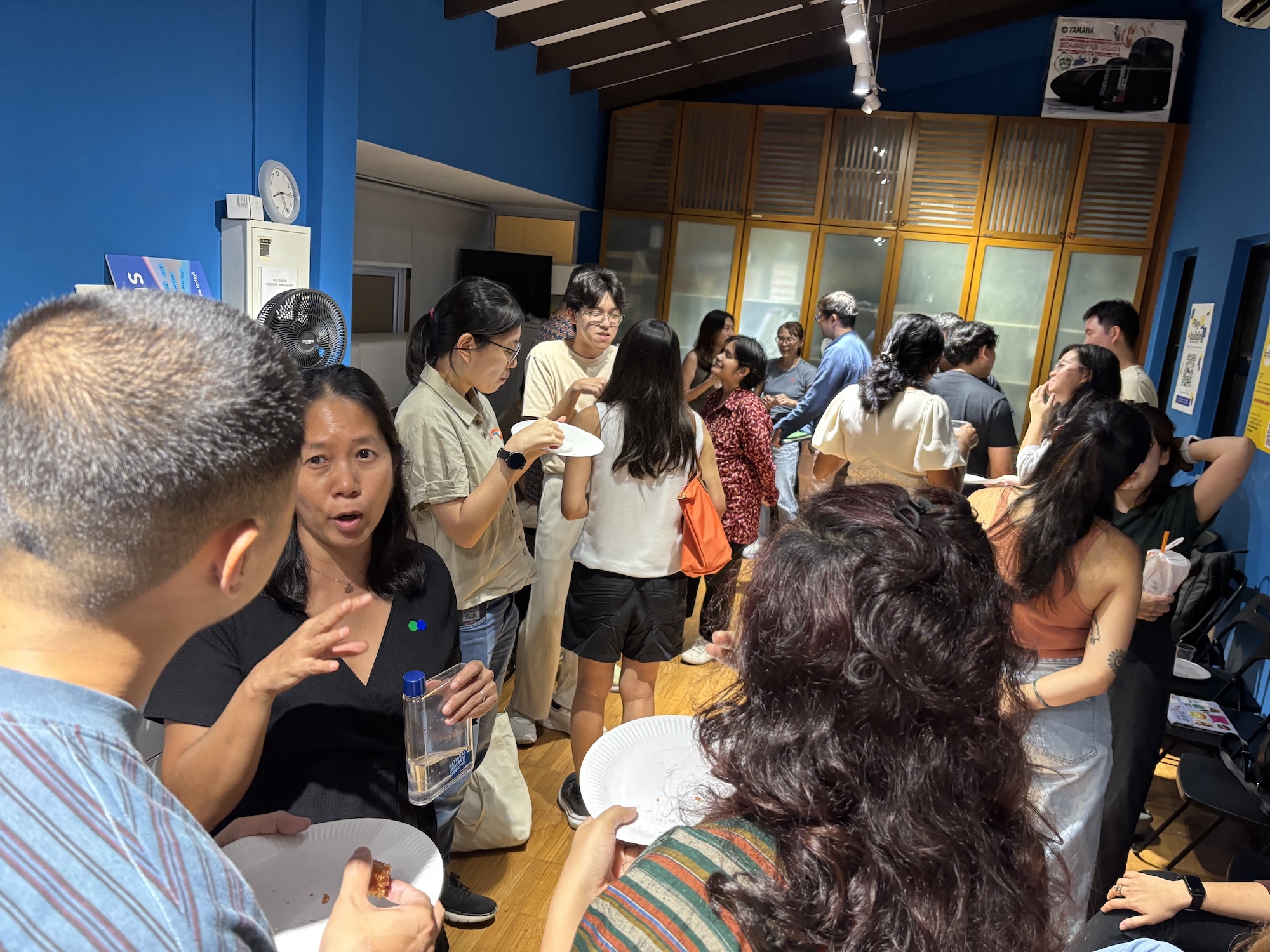 A large group of people talking and mingling in a small room.