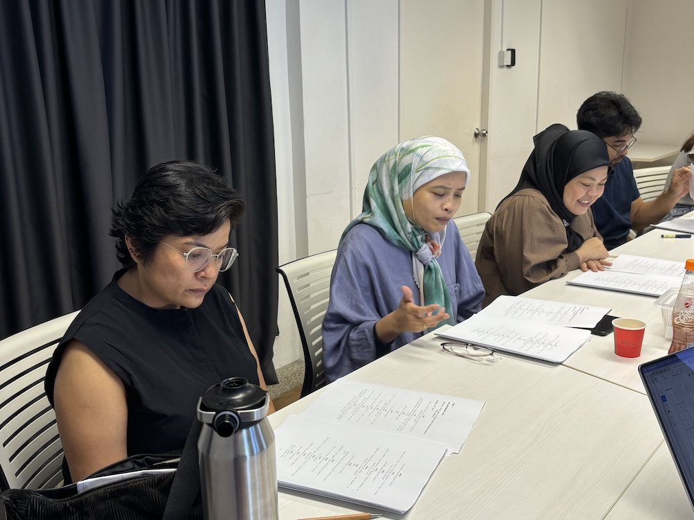 A photo of Farah Ong, Umi Ismail, Dalifah Shahril and Irfan Kasban seated around the table and reading from their scripts.